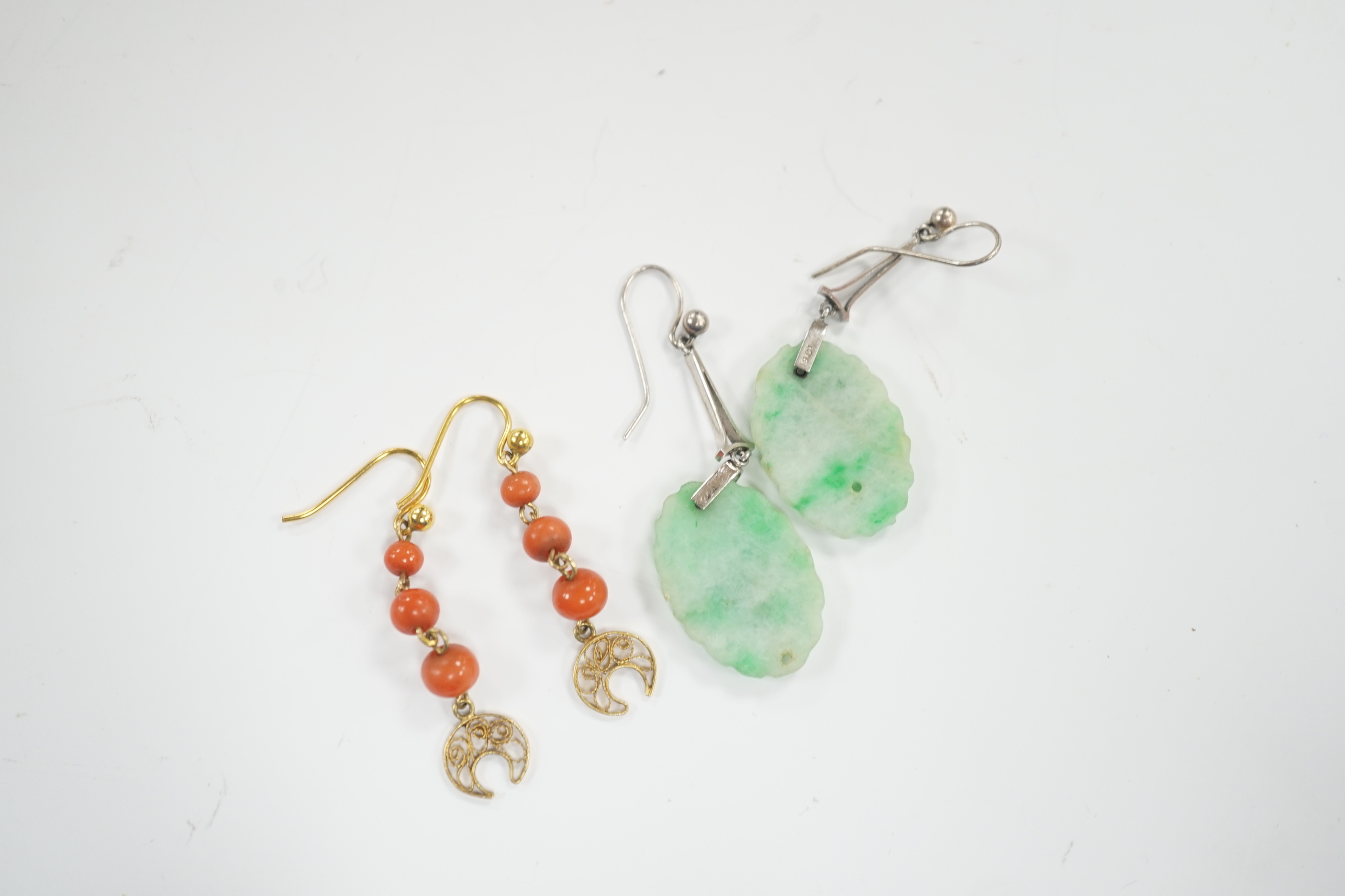 A pair of 9ct white metal and carved oval jade set drop earrings, jade 21mm and a pair of yellow metal and graduated three stone coral bead drop earrings, gross weight 6.2 grams.